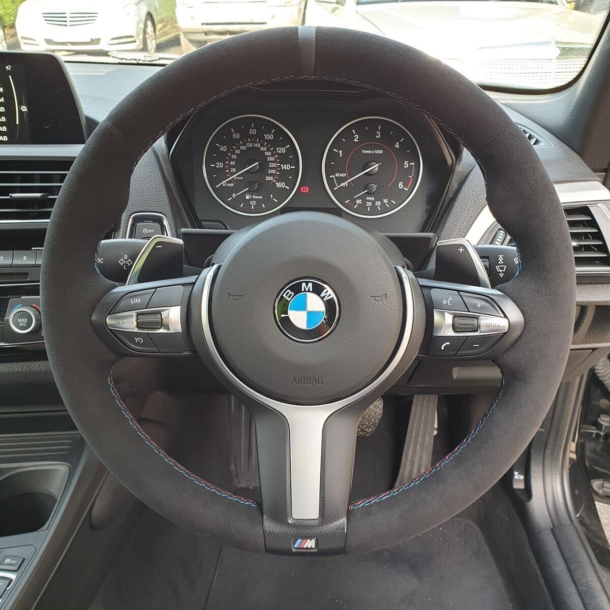 Custom BMW steering wheel upgrade with suede finish and M badge in luxury car interior