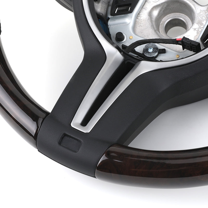 Close-up of BMW forged carbon steering wheel with black and wood trim detailing
