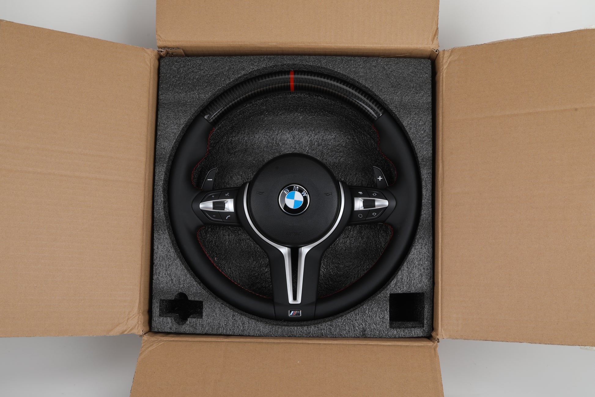 LED BMW steering wheel upgrade in black leather with red stitching and BMW logo in packaging