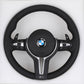 Black steering wheel with BMW logo on a white background