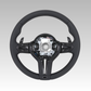 Black steering wheel with silver center on a gray background