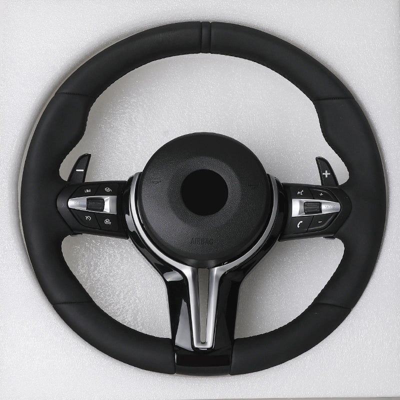 Black steering wheel with silver accents on a light gray background
