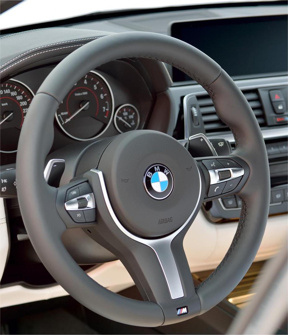 Steering wheel of a BMW car with dashboard in the background