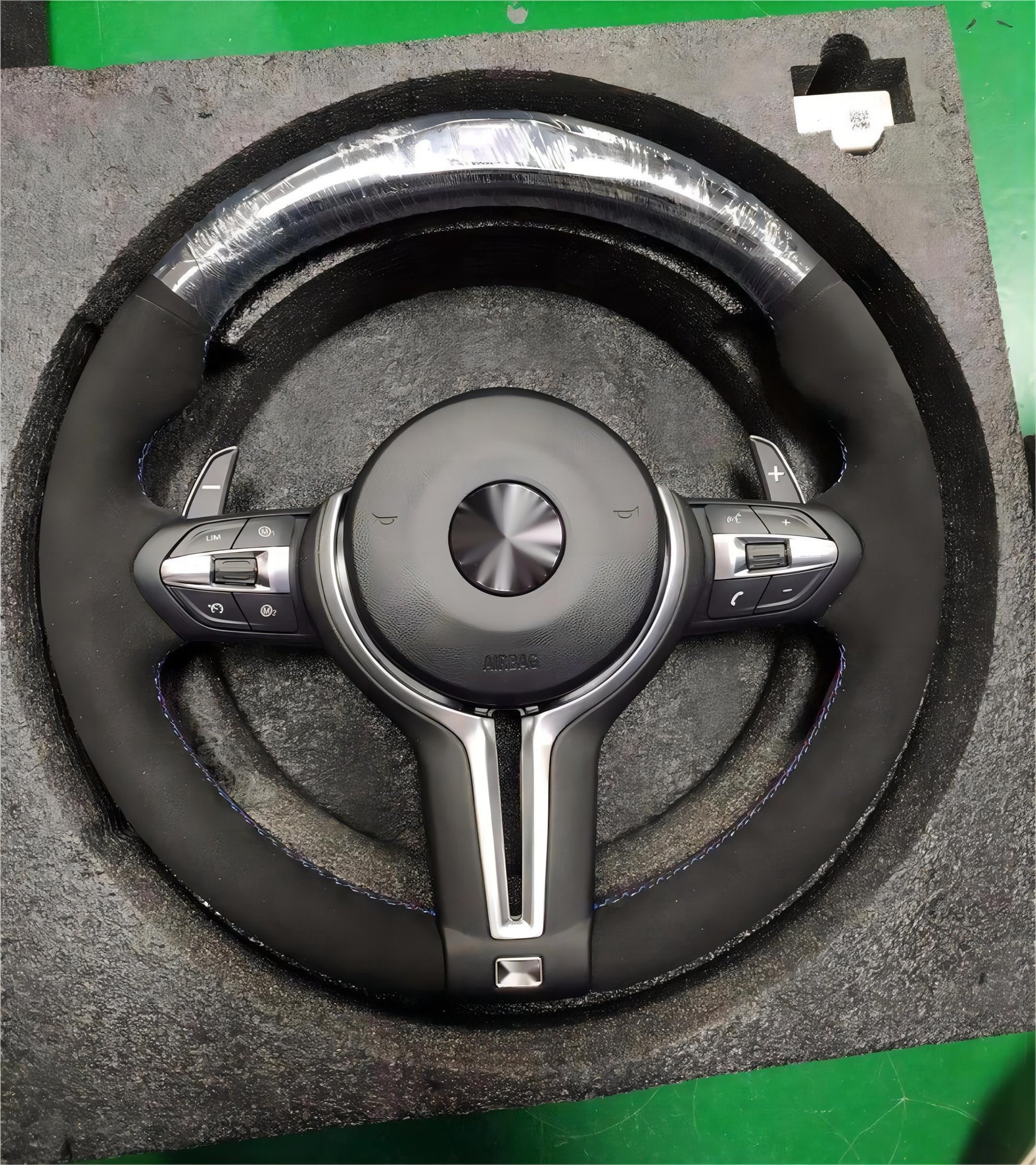 Steering wheel with silver accents on a gray cushioned surface