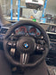 Steering wheel with BMW logo in a car interior, with a service counter in the background.