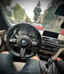 Car interior with a BMW steering wheel on a city street.