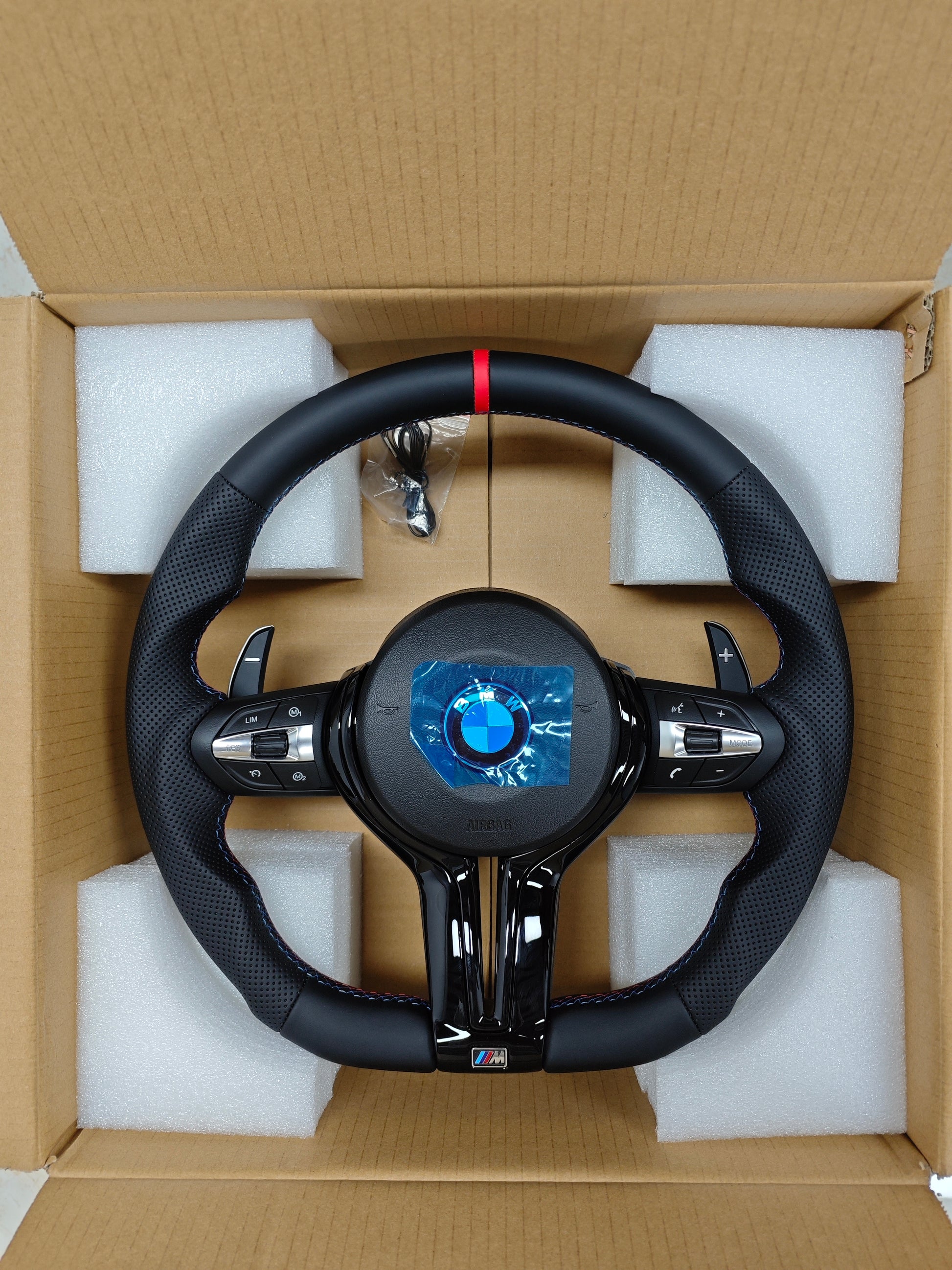 Car steering wheel with BMW logo in a cardboard box with foam padding