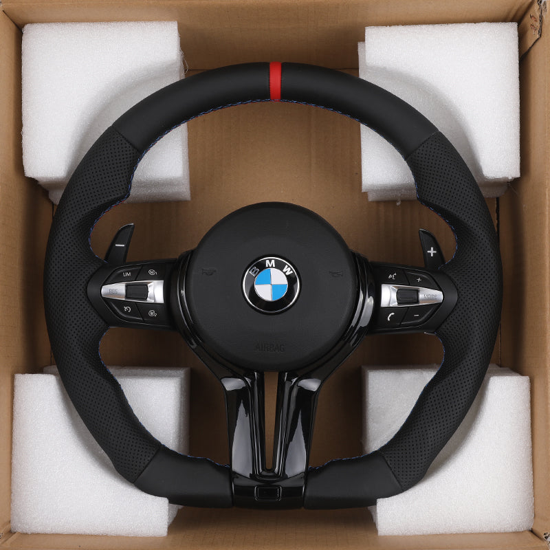 BMW carbon fiber steering upgrade in black with red center stripe and control buttons packaged in protective foam