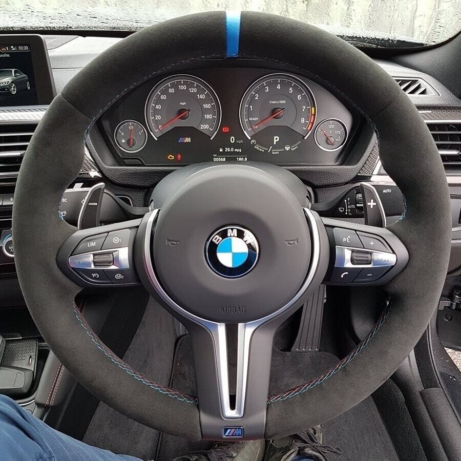 Custom BMW carbon steering wheel with suede grip and blue center stripe inside BMW sports car