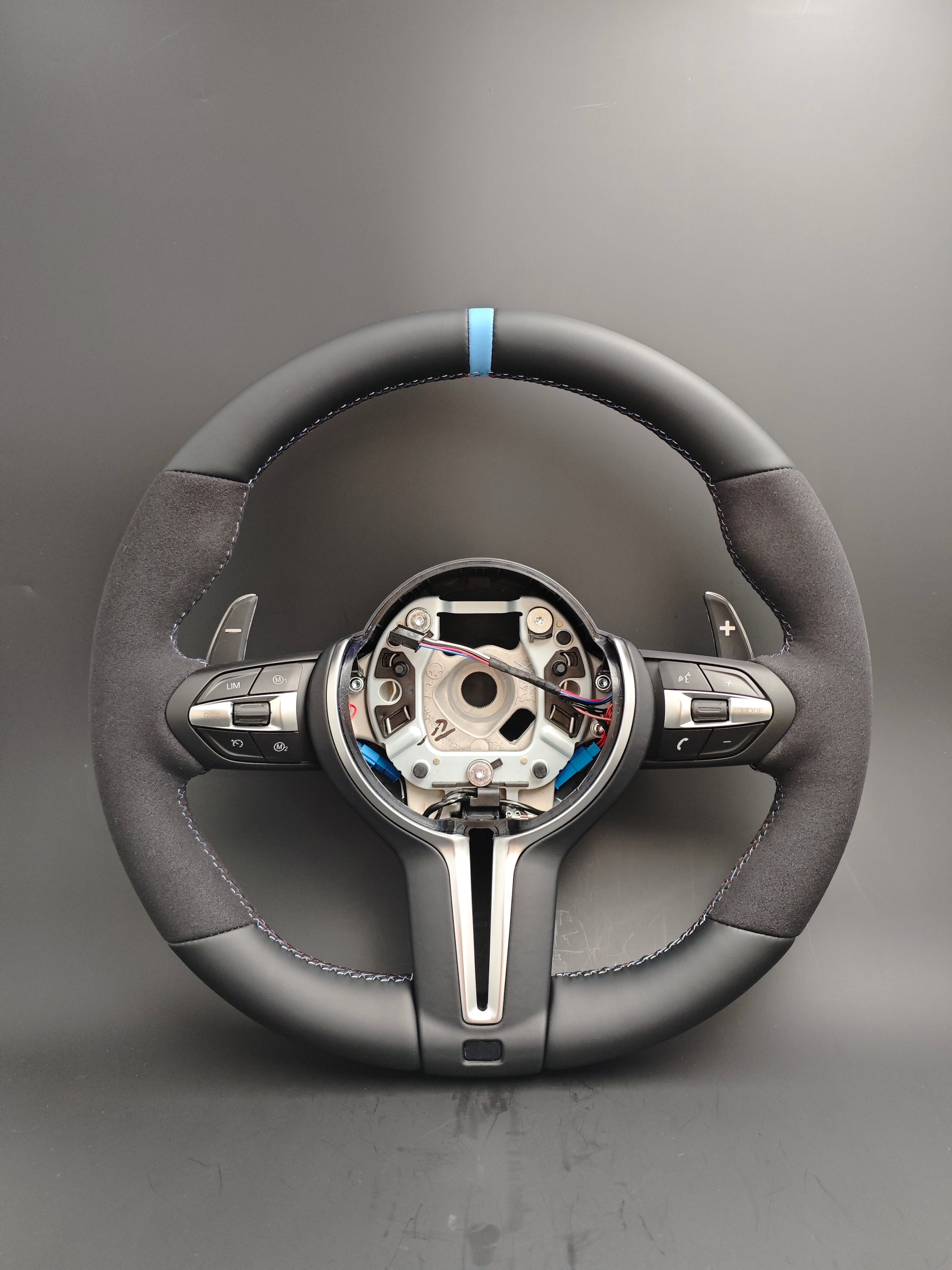 Black custom BMW steering wheel upgrade with blue center stripe and paddle shifters