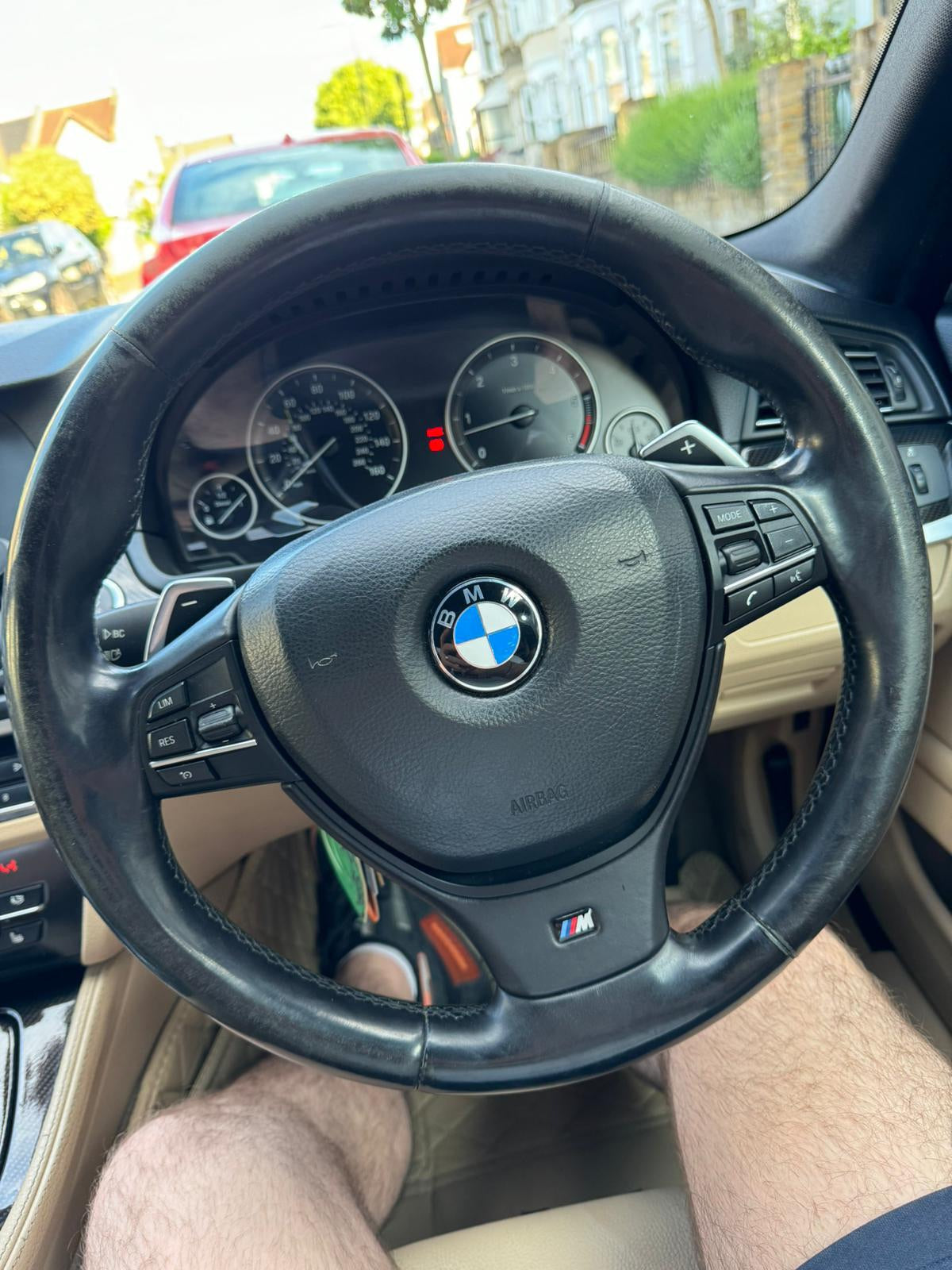 BMW custom M series steering wheel in black leather with control buttons and M badge in car interior