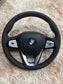 Forged carbon fiber BMW interior steering wheel with integrated control buttons and leather grip