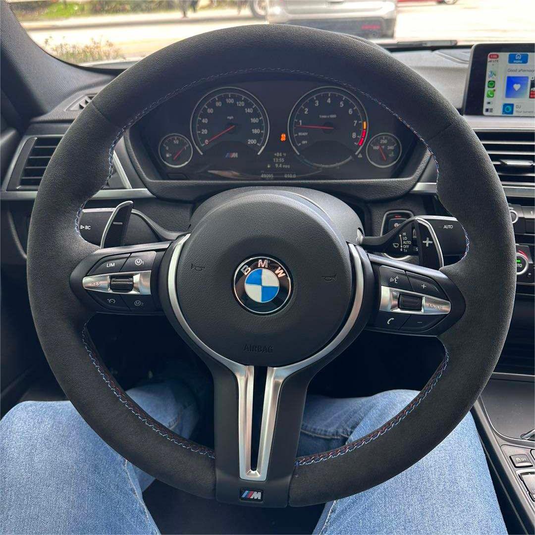 BMW forged carbon steering wheel with suede grip and integrated control buttons inside a car