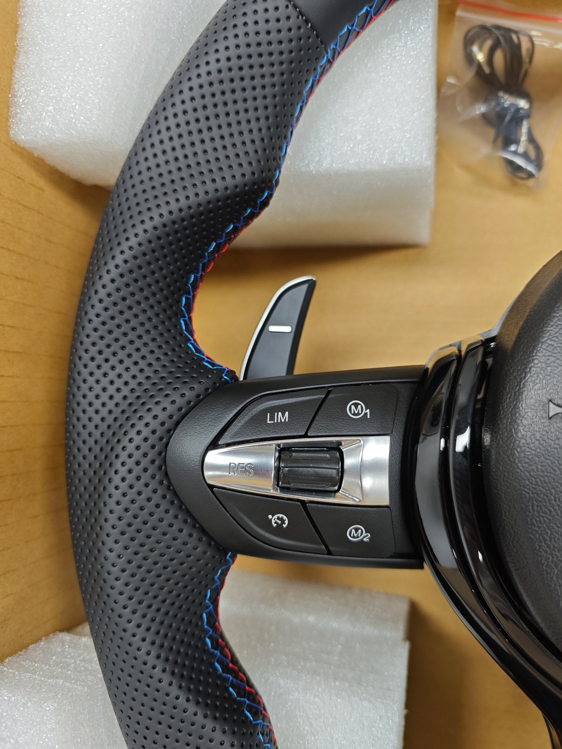 Close-up of BMW forged carbon steering wheel with perforated leather and control buttons