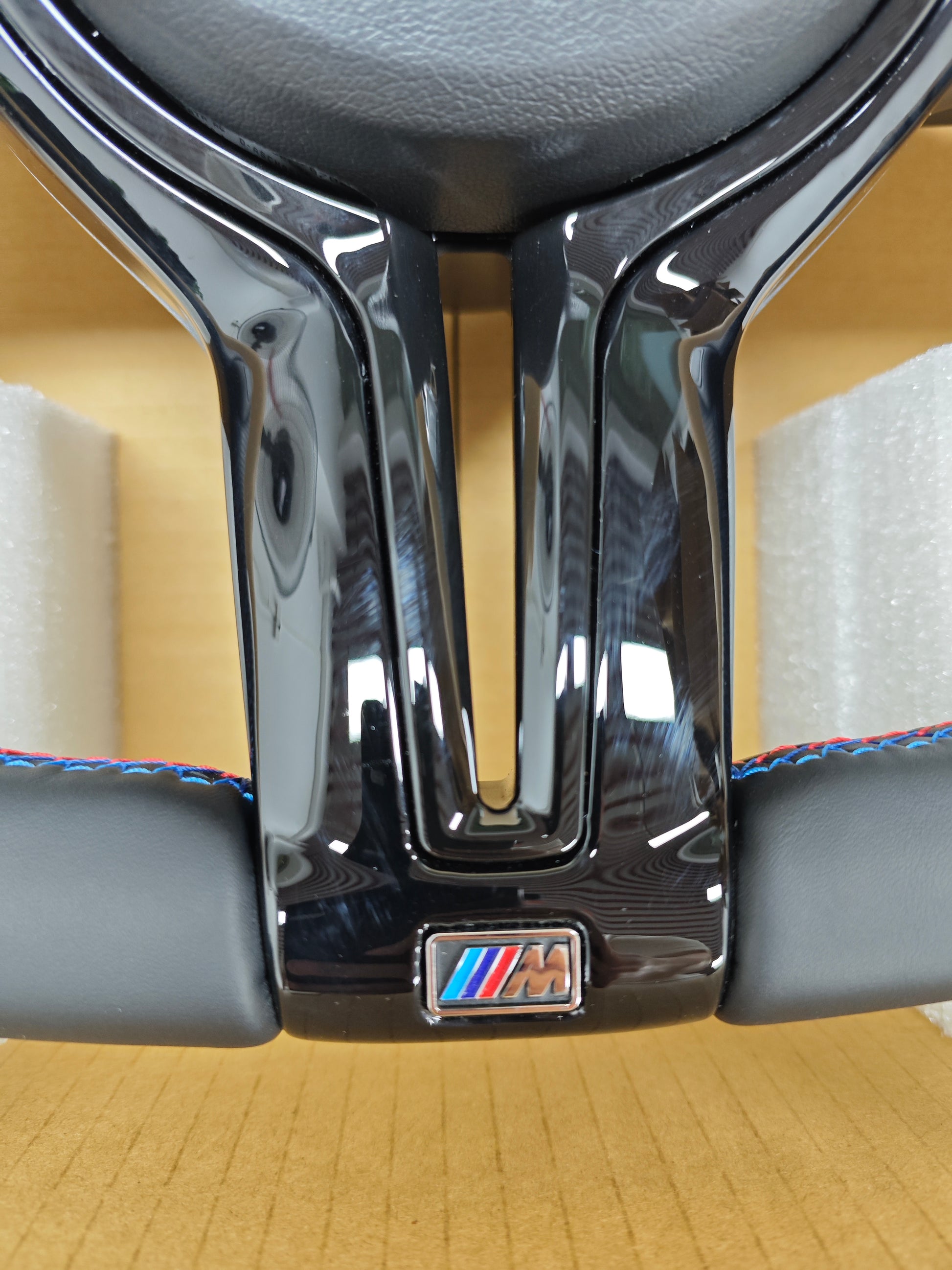 Close-up of BMW forged carbon steering wheel with M badge and black leather grip