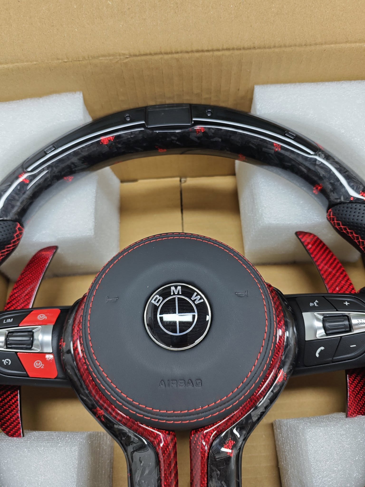 BMW performance steering wheel replacement with red stitching and carbon fiber design in protective packaging