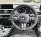 Steering wheel of a BMW car with dashboard in the background