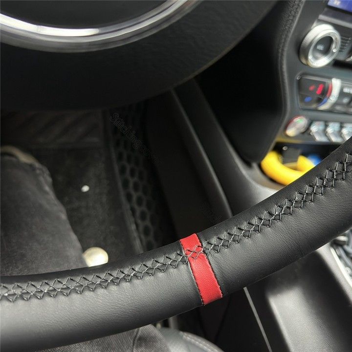 Close-up of Porsche leather steering wheel cover with black leather and red stitching detail inside car