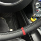 Close-up of Porsche leather steering wheel cover with black leather and red stitching detail inside car
